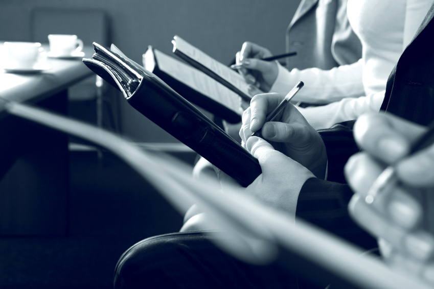 Row of hands writing a text at business conference